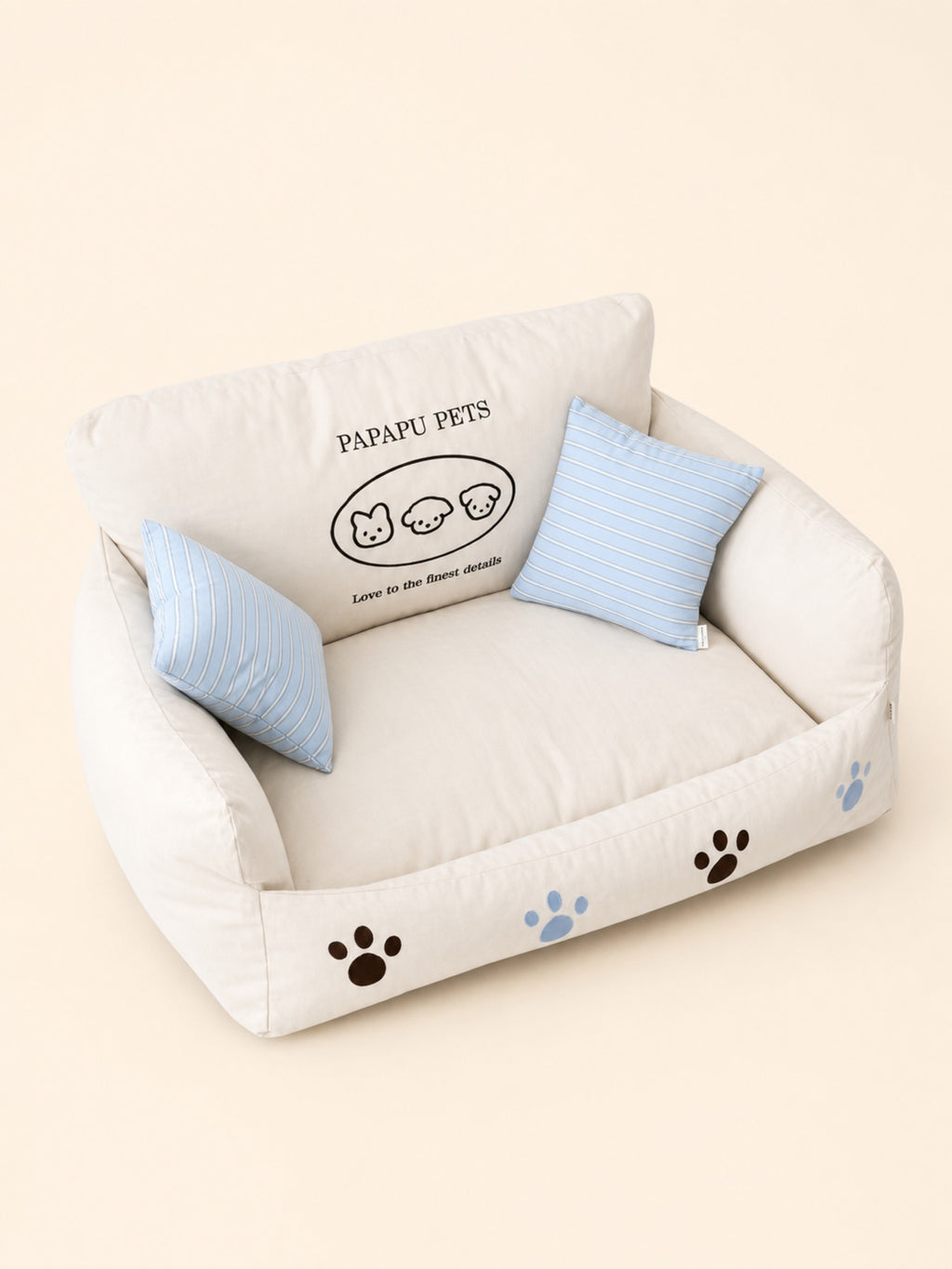 PrismTail Cove Sofa couch-style pet bed in cream with two striped throw pillows
