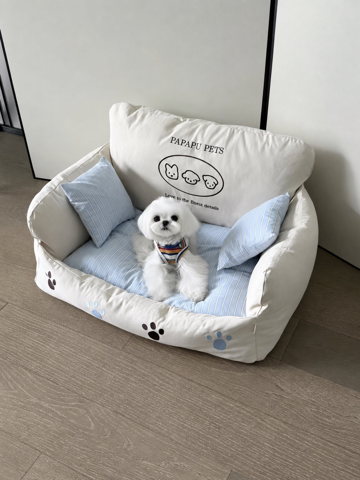 Small white dog resting on PrismTail Cove Sofa cream couch-style pet bed