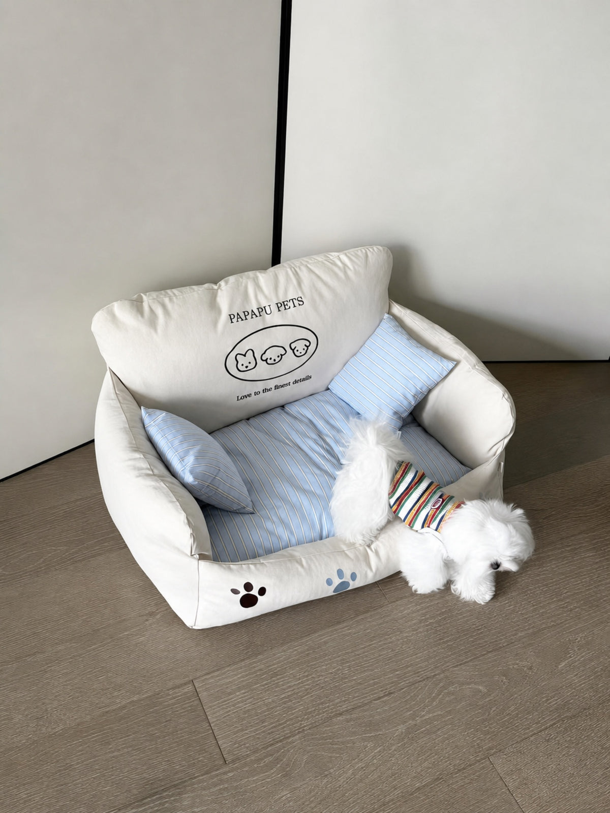 Maltese dog on PrismTail Cove Sofa cream couch-style pet bed with striped pillows